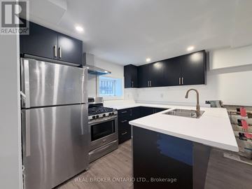 Hamilton (Delta) apartment for rent - A modern kitchen with a stainless steel refrigerator and black cabinets.
