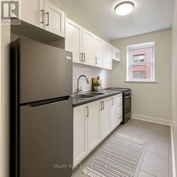 Toronto (Cabbagetown-South St. James Town) condo for rent - A kitchen with white cabinets and a black refrigerator.