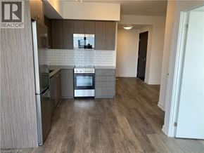 Kitchener condo for rent - A modern kitchen with a refrigerator, oven, and microwave.