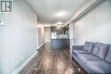 Brampton (Goreway Drive Corridor) condo for rent - A living room with a grey couch and a kitchen in the background.