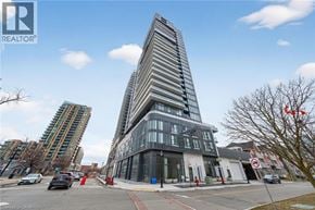 Burlington condo for rent - A tall building with a curved facade stands in front of a street with cars and other buildings.