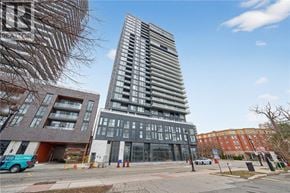 Burlington condo for rent - A tall, modern building with a glass facade stands in the foreground of a city street.