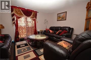 Brantford townhouse for rent - A living room with a black leather couch and a round table with a glass top.