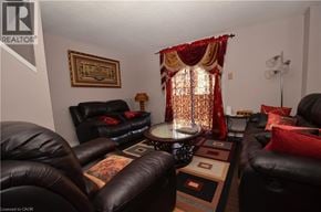 Brantford townhouse for rent - A living room with black leather furniture and a red curtain.