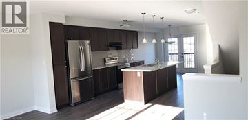 Kitchener townhouse for rent - A kitchen with dark brown cabinets and a stainless steel refrigerator.