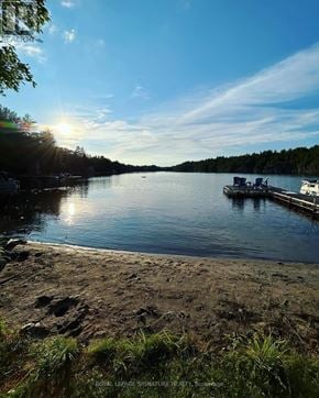 Gravenhurst (Muskoka (S)) apartment for rent - A serene lake with a dock and boats, and the sun setting in the background.