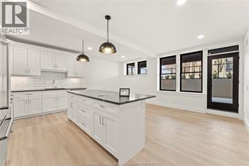 Amherstburg condo for rent - A modern kitchen with white cabinets and a black countertop.