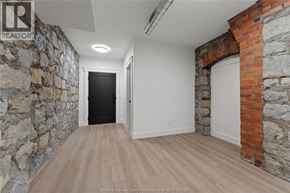 Amherstburg condo for rent - A hallway with a stone wall on the left and a brick wall on the right.
