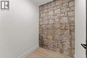 Amherstburg condo for rent - A stone wall in a room with a wooden floor.