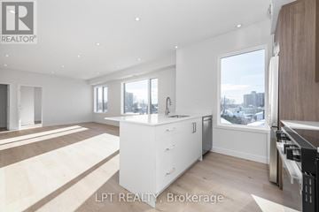 Ottawa multi-family for rent - A modern kitchen with white cabinets and a large window.