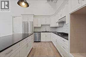 Amherstburg condo for rent - A kitchen with white cabinets and a black countertop.