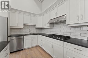Amherstburg condo for rent - A kitchen with white cabinets and a black countertop.