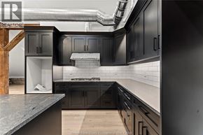 Amherstburg condo for rent - A modern kitchen with dark cabinets and a wooden staircase.