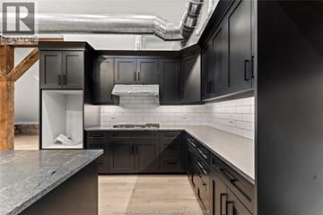 Amherstburg condo for rent - A modern kitchen with dark cabinets and a wooden staircase.