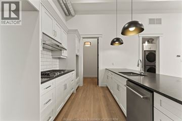 Amherstburg condo for rent - A modern kitchen with white cabinets and a wooden floor.