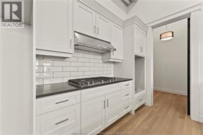 Amherstburg condo for rent - A kitchen with white cabinets and a black stove top.