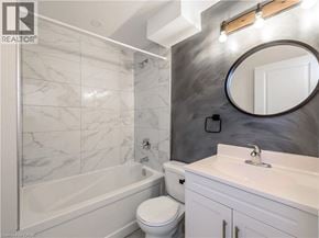 St. Catharines apartment for rent - A bathroom with a marble tile shower, white toilet, and sink.