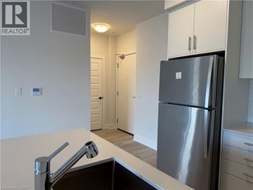 Kitchener condo for rent - A modern kitchen with a stainless steel refrigerator and a sink.