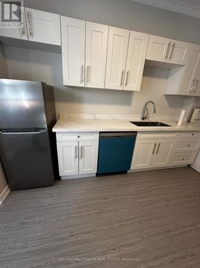 Toronto (North St. James Town) apartment for rent - A kitchen with a black refrigerator, white cabinets, and a blue island.