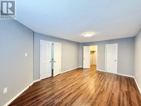Ajax (Central) multi-family for rent - A room with wooden flooring and white walls, with three doors and a brokerage sign.