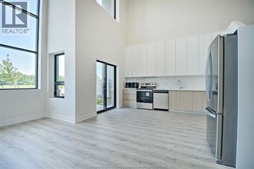 Lasalle condo for rent - A modern kitchen with white cabinets and a wooden floor.