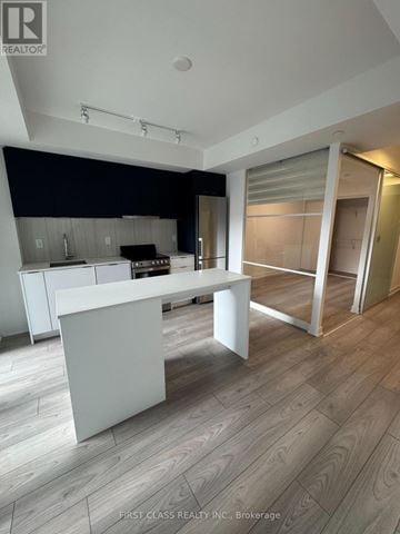 Toronto (Clanton Park) condo for rent - A modern kitchen with a white island and wooden flooring.