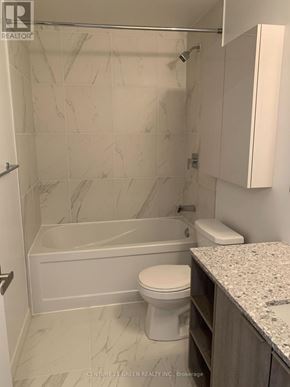 Toronto (Clanton Park) condo for rent - A white toilet sits next to a bathtub in a bathroom.