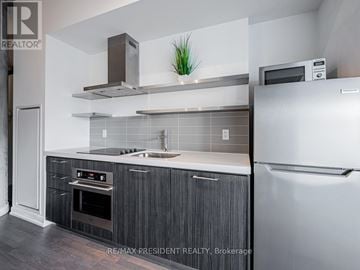 Toronto (Waterfront Communities) condo for rent - A modern kitchen with a stainless steel refrigerator and a black and white color scheme.