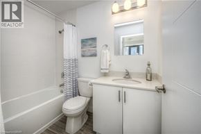 Kitchener condo for rent - A white bathroom with a toilet, sink, and shower.