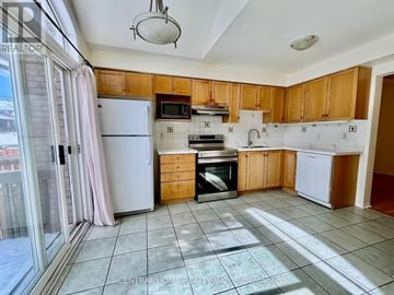 Richmond Hill (Rouge Woods) townhouse for rent - A kitchen with wooden cabinets and a white refrigerator.