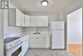 Port Hope condo for rent - A white kitchen with a refrigerator, oven, and cabinets.