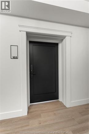 Amherstburg condo for rent - A black door is in a white room with a number 103 on the wall.