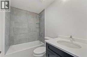 Amherstburg condo for rent - A bathroom with a white tub, sink, and toilet.