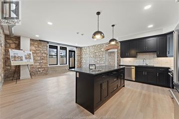 Amherstburg condo for rent - A kitchen with black cabinets and a stone wall.