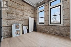 Amherstburg condo for rent - A room with stone walls and wooden floors, with a poster and a white curtain.