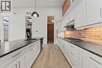 Amherstburg condo for rent - A kitchen with white cabinets and a brick wall.