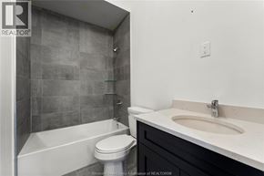 Amherstburg condo for rent - A bathroom with a white toilet and a white sink.
