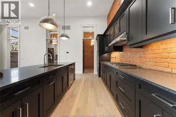 Amherstburg condo for rent - A kitchen with black cabinets and a brick wall.