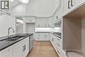 Amherstburg condo for rent - A kitchen with white cabinets and a black countertop.