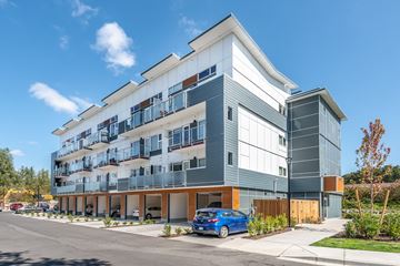 Brentwood Bay apartment for rent - A modern multi-story building with a blue car parked in front.