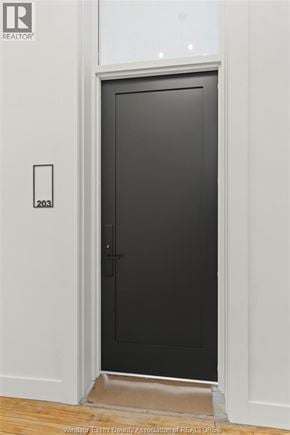 Amherstburg condo for rent - A black door with a handle and a number 203 on the wall.