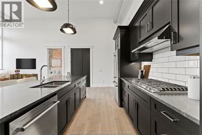 Amherstburg condo for rent - A modern kitchen with black cabinets and stainless steel appliances.