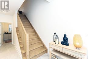 Wasaga Beach apartment for rent - A wooden staircase leads to a white wall with a statue and a lantern on a table.