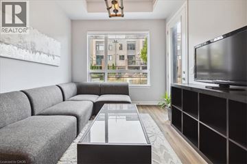 Grimsby condo for rent - A living room with a grey couch and a coffee table in front of a large window.