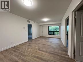 Windsor condo for rent - A spacious room with wooden flooring and white walls.