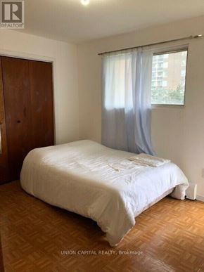 Toronto (Weston-Pellam Park) multi-family for rent - A bedroom with a bed, wooden floor, and a window with curtains.