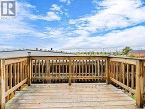 Hamilton townhouse for rent - A wooden deck with a railing and a blue sky with clouds in the background.