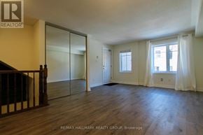 Ottawa townhouse for rent - A spacious room with wooden floors and a glass door leading to another room.