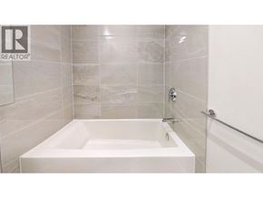 Vancouver apartment for rent - A white bathtub in a bathroom with tiled walls.