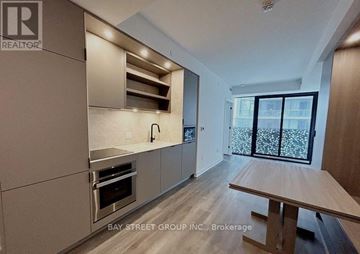 Toronto (Church-Yonge Corridor) condo for rent - A modern kitchen with a wooden table and stainless steel appliances.